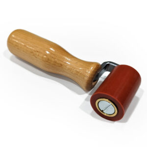 Die Andrückrolle ist ein kleines Werkzeug mit einem glatten Holzgriff und einer roten zylindrischen Gummirolle zum Andrücken oder Glätten von Oberflächen.